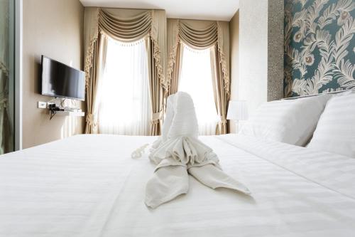 a bedroom with a white bed with a towel on it at Courtyard khaoyai by JP in Mu Si