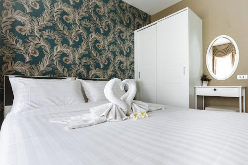 a bedroom with a bed with white sheets and a mirror at Courtyard khaoyai by JP in Mu Si