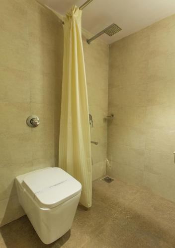 a bathroom with a white toilet and a shower at Aura One Hotel in Cochin