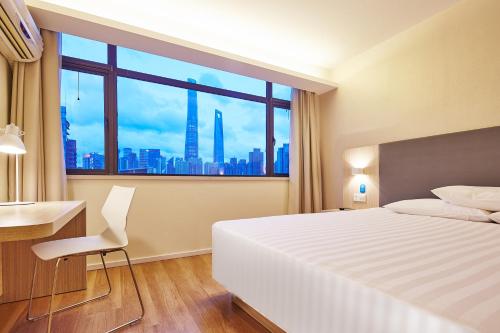 蘭州市にあるLavande Hotel Lanzhouのベッド、デスク、窓が備わるホテルルームです。