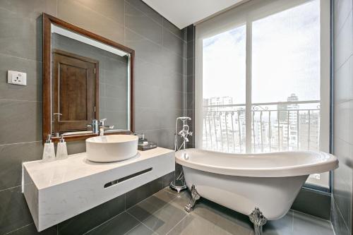 a bathroom with a tub and a sink and a window at Cosmos Hotel Danang in Da Nang