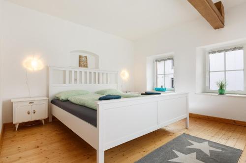 a bedroom with a white bed and two windows at Auszeit-Eifel Eifelhaus "Burgaß 1807" Sauna & Badezuber in Willwerscheid