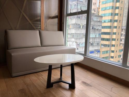 a coffee table in a room with a couch and a window at Homy Residence in Hong Kong