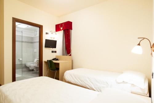 a hotel room with two beds and a mirror at Family Hotel La Perla in Fiera di Primiero