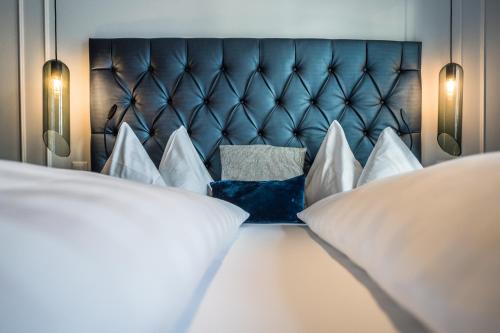 a bed with a blue headboard and white pillows at Parkhotel Gunten – Beach & Spa in Gunten