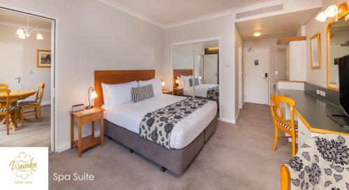 a hotel room with a large bed and a table at Wairakei Resort Taupo in Taupo
