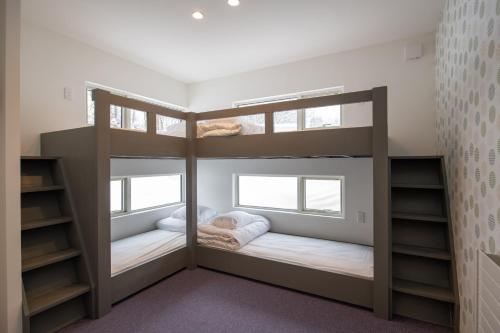 a room with two bunk beds and two windows at Mountain Butterfly in Niseko