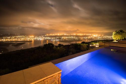 a swimming pool with a view of a city at night at Alkira Lodge in Brenton-on-Sea