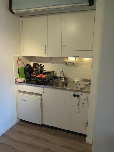 a kitchen with white cabinets and a sink at Swiss Seeblick Apartment mit Hotelanbindung in Beatenberg