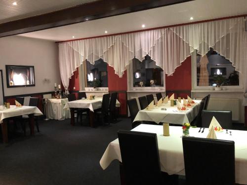 a dining room with white tables and chairs and curtains at Hotel & Restaurant Blume in Wolfsburg
