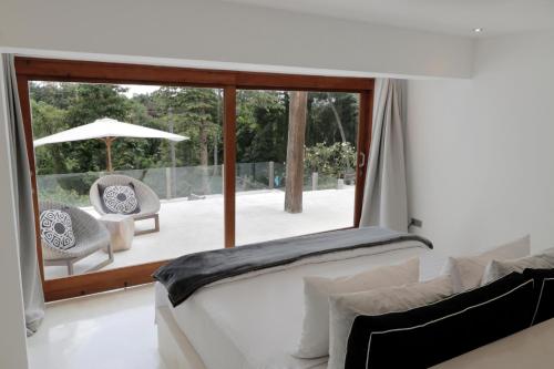 a bedroom with a bed and a patio with an umbrella at The Apartments Ubud in Ubud