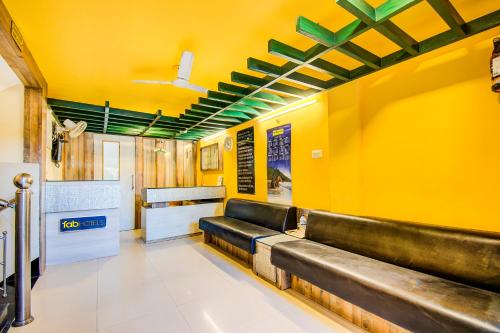 uma sala de espera com bancos numa parede amarela em FabHotel Kumar Vijay Nagar em Indore