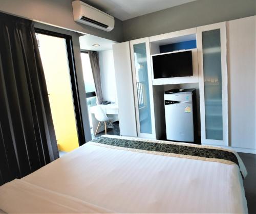 a bedroom with a white bed and a large window at iSanook Bangkok in Bangkok