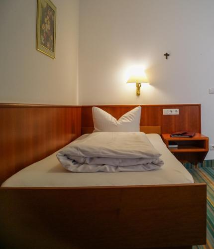 a bedroom with a bed with white sheets and a lamp at Landhotel Geyer in Kipfenberg
