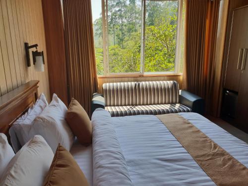 a bedroom with a bed and a couch and a window at Daddy's Guest Home in Adams Peak