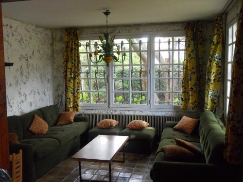 a living room with green couches and windows at La palombe in Mimizan-Plage