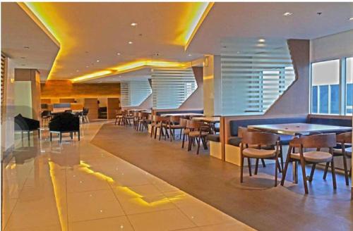 um restaurante com mesas e cadeiras num edifício em Green Residences Staycation by PBYY with Complimentary breakfast for 2 em Manila