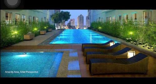 a large swimming pool with benches next to a building at Green Residences Staycation by PBYY with Complimentary breakfast for 2 in Manila