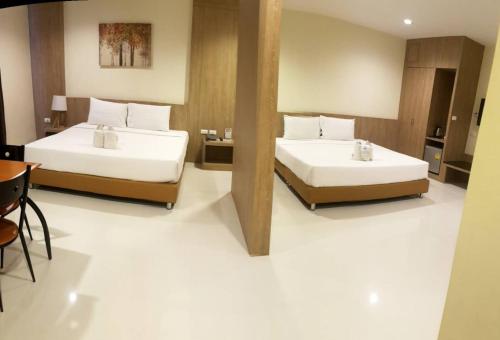 a bedroom with two beds and a table and chairs at OMG Hotel in Khon Kaen