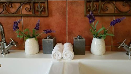 a bathroom sink with three vases with towels and flowers at Barossa Glen ~ Henri's Cottage ~ Bed & Breakfast in Rosedale