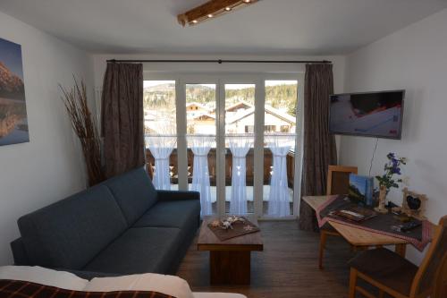 a living room with a blue couch and a window at Haus Erli in Mittenwald