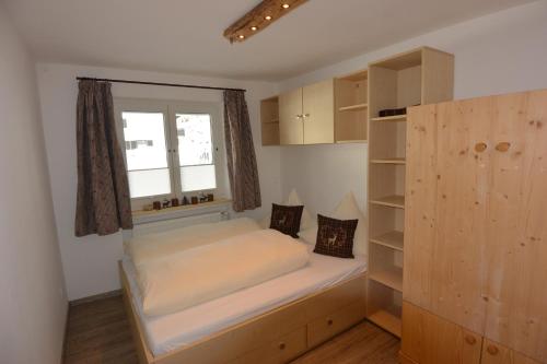 a bedroom with a bed and a window and shelves at Haus Erli in Mittenwald