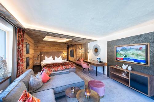 a hotel room with a bed and a couch at Hotel Alpin Spa Tuxerhof in Tux