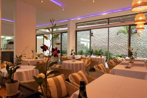 a restaurant with white tables and chairs and windows at Patong Heights in Patong Beach