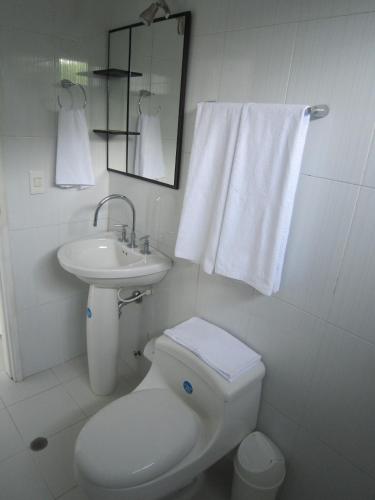 a white bathroom with a toilet and a sink at Hotel Valmar in Cartagena de Indias