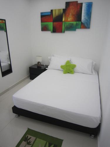 a bedroom with a white bed with a painting on the wall at Hotel Valmar in Cartagena de Indias