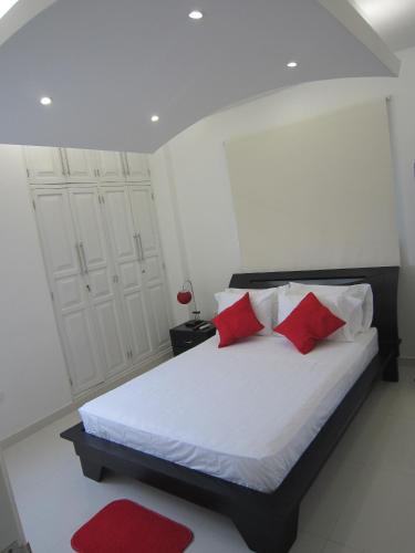 a bedroom with a white bed with red pillows at Hotel Valmar in Cartagena de Indias
