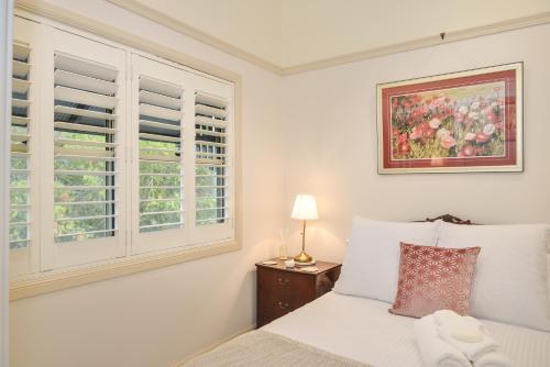 a white bedroom with a bed and a window at The Guesthouse Maleny in Maleny
