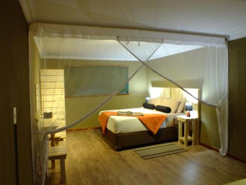 a bedroom with a canopy bed in a room at Thobolo's Bush Lodge in Kachikau