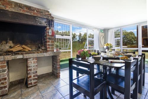 a dining room table with a fire place in front of it at Kingfisher Hollow in Gordonʼs Bay