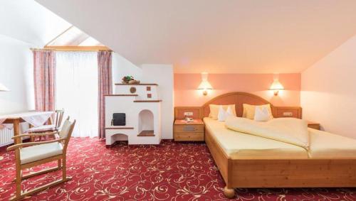 a hotel room with a bed and a chair at Hotel Krimmlerfälle in Krimml