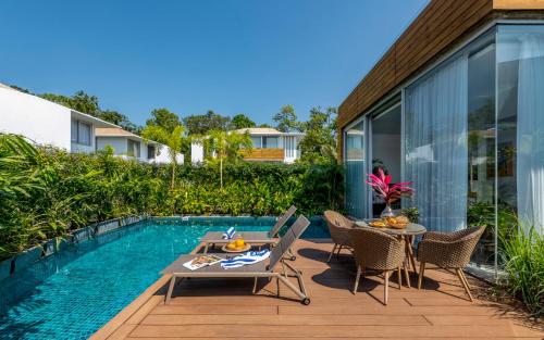 a patio with a table and chairs next to a swimming pool at La Maroma 3 BHK Splendid Villas in Anjuna - Pvt Pool- Garden & Caretaker in Vagator