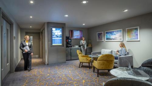 a woman is standing in a lobby with a room at Maldron Hotel Newcastle in Newcastle upon Tyne