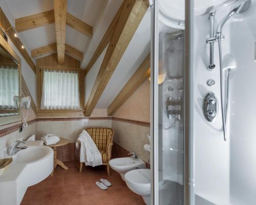 a bathroom with two sinks a toilet and a shower at Hotel B&B Andreas in Canazei