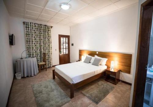 um quarto com uma cama e uma mesa em Praia Accommodation em São Tomé