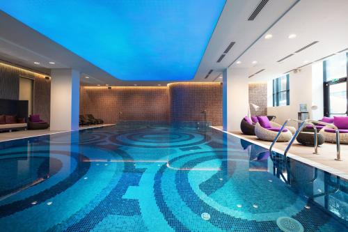 a swimming pool in a hotel lobby with a blue ceiling at Novotel Almaty City Center in Almaty
