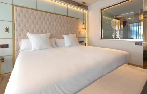 a large white bed with a large headboard and a mirror at Barceló Ourense in Ourense