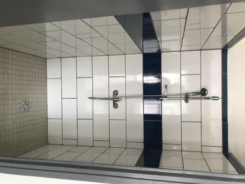 La salle de bains est pourvue d'une douche et de carrelage blanc et bleu. dans l'établissement L'Escale Royale, à Salazie