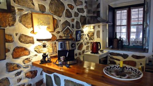 - une cuisine avec un mur en pierre et une cafetière sur un comptoir dans l'établissement Tramontana, à Hydra