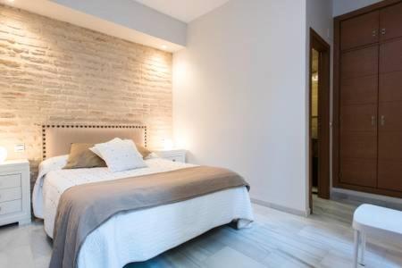 a bedroom with a bed and a brick wall at Apartment Villegas in Seville