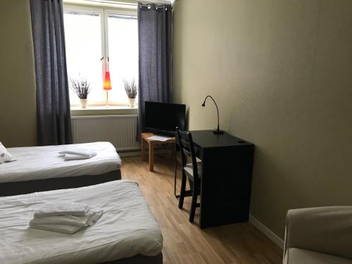 a room with two beds and a desk with a computer at Grand Hotell & Hostel Strömsund in Strömsund