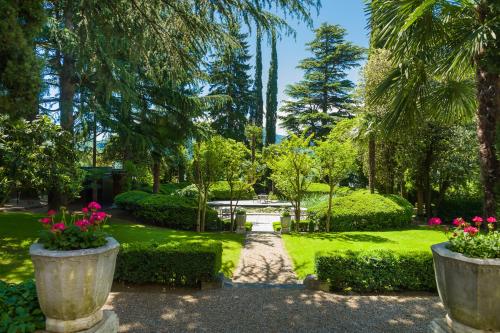 un giardino con fiori rosa in grandi vasi di cemento di Villa Eden a member of Leading Hotels of the World a Merano