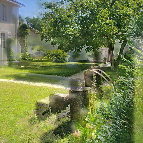 a garden with a stone fountain in the grass at Maison d'Hôtes Lassaubatju in Hontanx