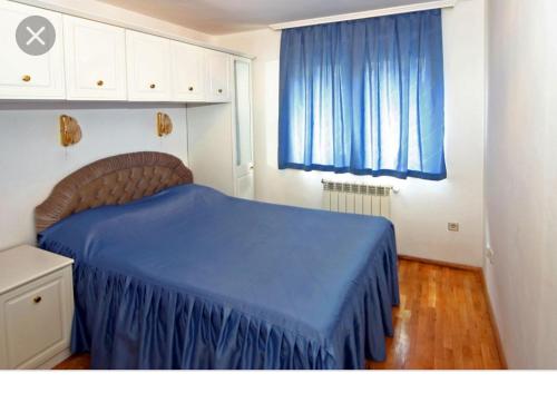 a bedroom with a blue bed and a blue curtain at Apartment Pier in Varna City