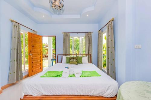 a bedroom with a large white bed with green pillows at RAT VILLA in Ban Pa Khlok