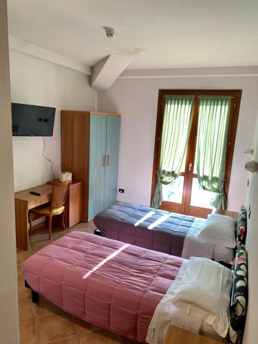 a bedroom with two beds and a desk and a table at Hotel Riviera Ristorante La Briciola in San Bernardino